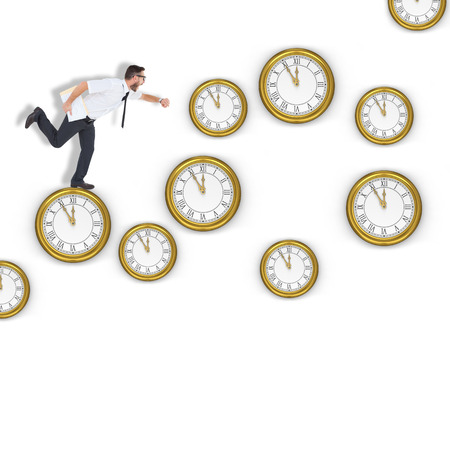 Geeky young businessman running late against clocksの写真素材