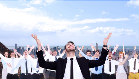 Businessman cheering with hands raised against large city on the horizonの写真素材