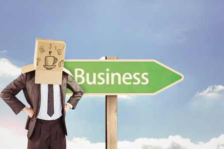 Anonymous businessman with hands on hips against business road signの写真素材