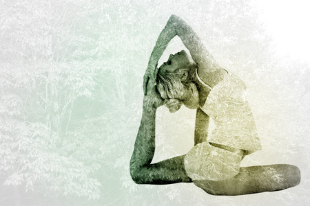 Toned young woman doing the pigeon pose against peaceful autumn scene in forestの写真素材