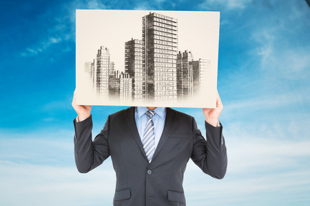 Businessman hiding head with a box against blue skyの写真素材