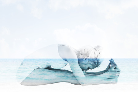 Toned woman doing the paschimottanasana pose against beach sceneの写真素材