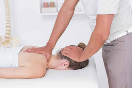 Physiotherapist doing neck massage to his patient in medical officeの写真素材