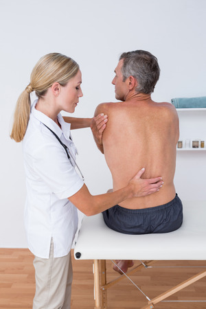 Doctor examining her patient back in medical officeの写真素材
