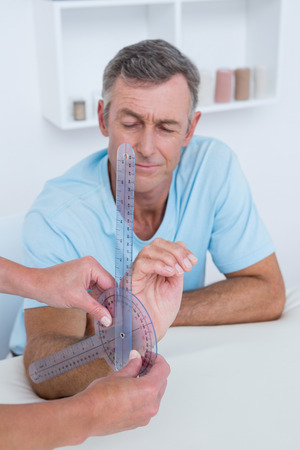 Doctor measuring wrist with goniometer in medical officeの写真素材