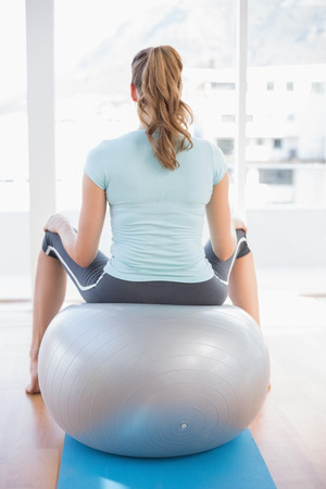 Woman sitting on exercise ball in fitness studioの写真素材