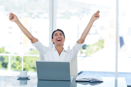 Businesswoman celebrating a great success in her officeの写真素材