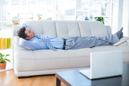 Businessman lying on couch in living room