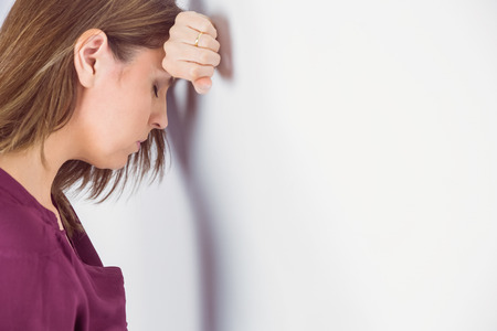 Depressed man leaning her head against a wall on white backgroundの写真素材