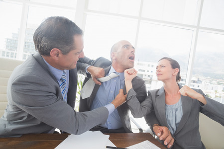 Business partners fighting together in an officeの写真素材