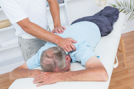 Physiotherapist doing neck massage to his patient in medical officeの写真素材