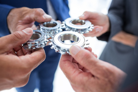 Business colleagues holding cog in the officeの写真素材