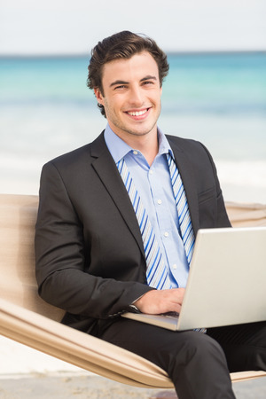 Businessman using laptop on the hammock at the beachの写真素材