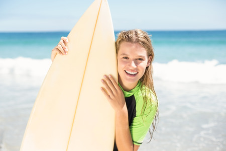 Pretty blonde woman holding surf board at the beachの写真素材