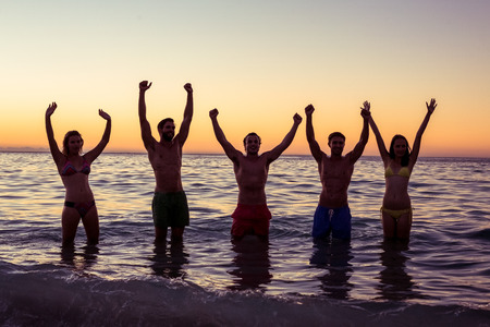 Happy friends having fun in the water at the beachの写真素材