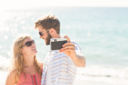 Happy couple taking selfie at the beachの写真素材
