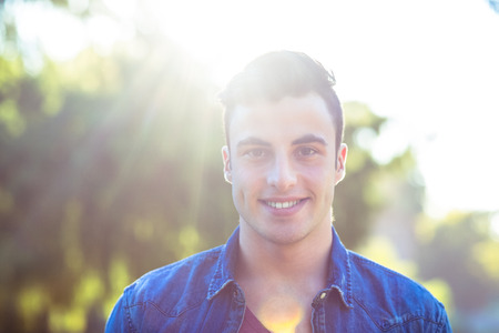 Happy hipster looking at camera on a sunny dayの写真素材