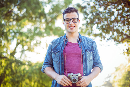 Handsome hipster holding vintage camera on a sunny dayの写真素材