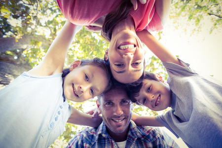 Happy family in the park huddling in circle on a sunny dayの写真素材