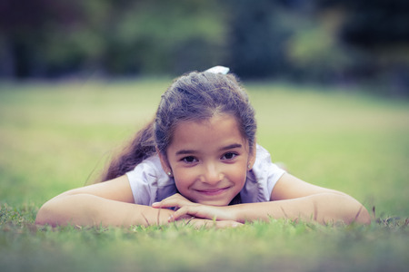 Smiling little girl looking at the camera in the parkの写真素材