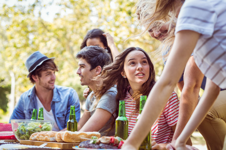 Happy friends in the park having lunch on a sunny dayの写真素材