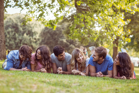 Friends lying and talking in the park on a sunny dayの写真素材