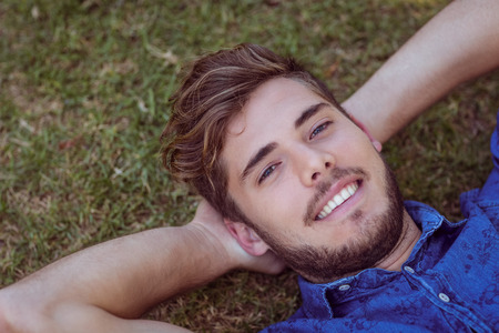 Young man lying down in the park on a summers dayの写真素材