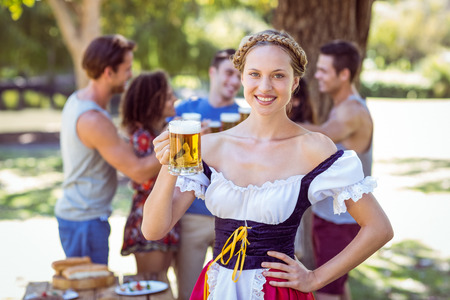 Pretty oktoberfest blonde toasting in the park on a sunny dayの写真素材