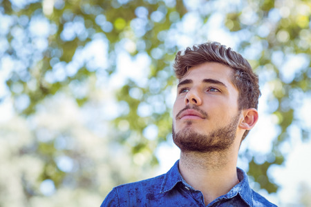 Handsome thinking hipster in the park on a sunny dayの写真素材