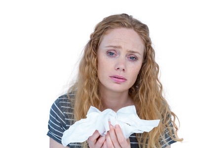 Sick blonde woman holding paper tissue on white backgroundの写真素材