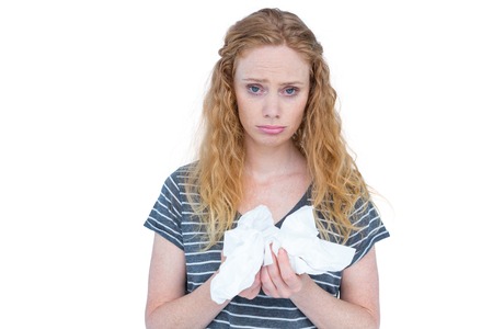 Sick blonde woman holding paper tissue on white backgroundの写真素材