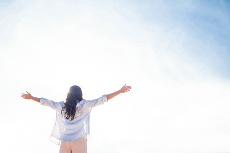 Happy woman with arms outstretched at the beach on a sunny dayの写真素材