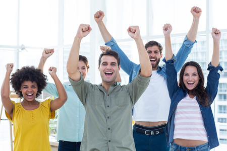 Young creative business people gesturing arm up at office