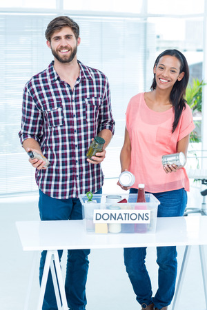 Portrait of smiling young friends volunteers separating foodstuffsの写真素材