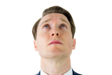 Serious businessman looking at top on white backgroundの写真素材