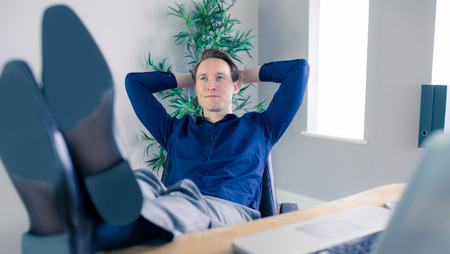 Smiling businessman relaxing in a swivel chair in his office