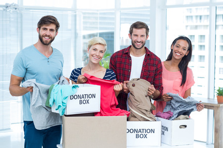 Portrait of smiling young friends volunteers separating clothesの写真素材