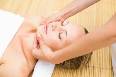 Close up of an attractive young woman receiving facial massage at spa centerの写真素材