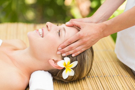 Close up of an attractive young woman receiving facial massage at spa centerの写真素材