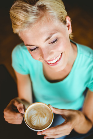 Pretty blonde holding cup of coffee at the cafeの写真素材