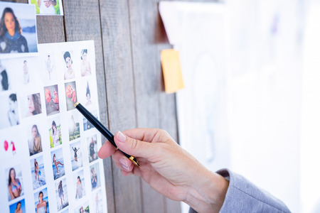 Creative businesswoman pointing pictures with pen in officeの写真素材