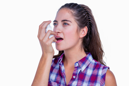 Pretty brunette woman using asthma inhaler on white background