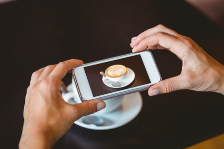 Woman taking picture with her smartphone at the cafe