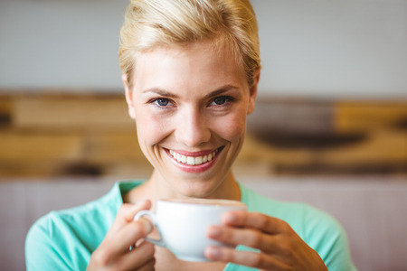 Pretty blonde holding cup of coffee at the cafeの写真素材