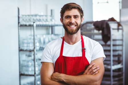 Handsome barista smiling at the camera at the cafeの写真素材
