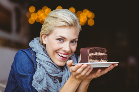 Smiling blonde holding a chocolate cake while looking at the cameraの写真素材