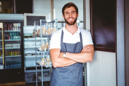 Smiling server in apron arm crossed at the bakeryの写真素材