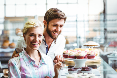 Cute couple on a date looking at cakes at the bakeryの写真素材