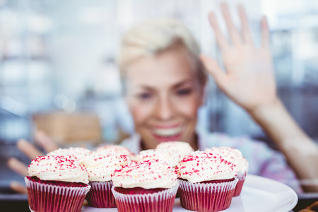 Astonished pretty woman looking at cup cakes at the bakeryの写真素材