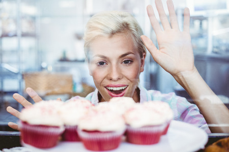 Astonished pretty woman looking at cup cakes at the bakeryの写真素材